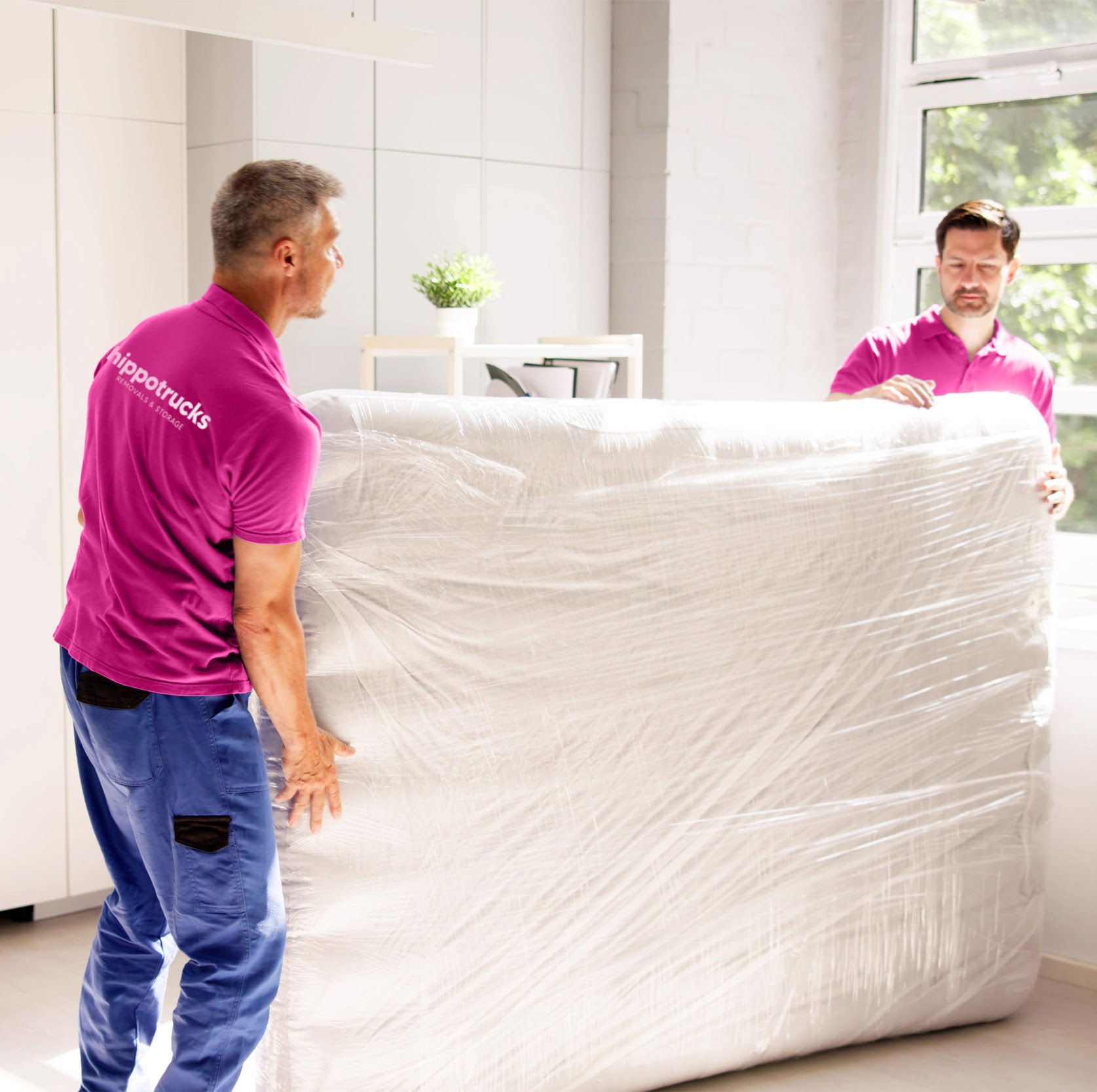 Hippotrucks movers wrapping and carrying a large mattress